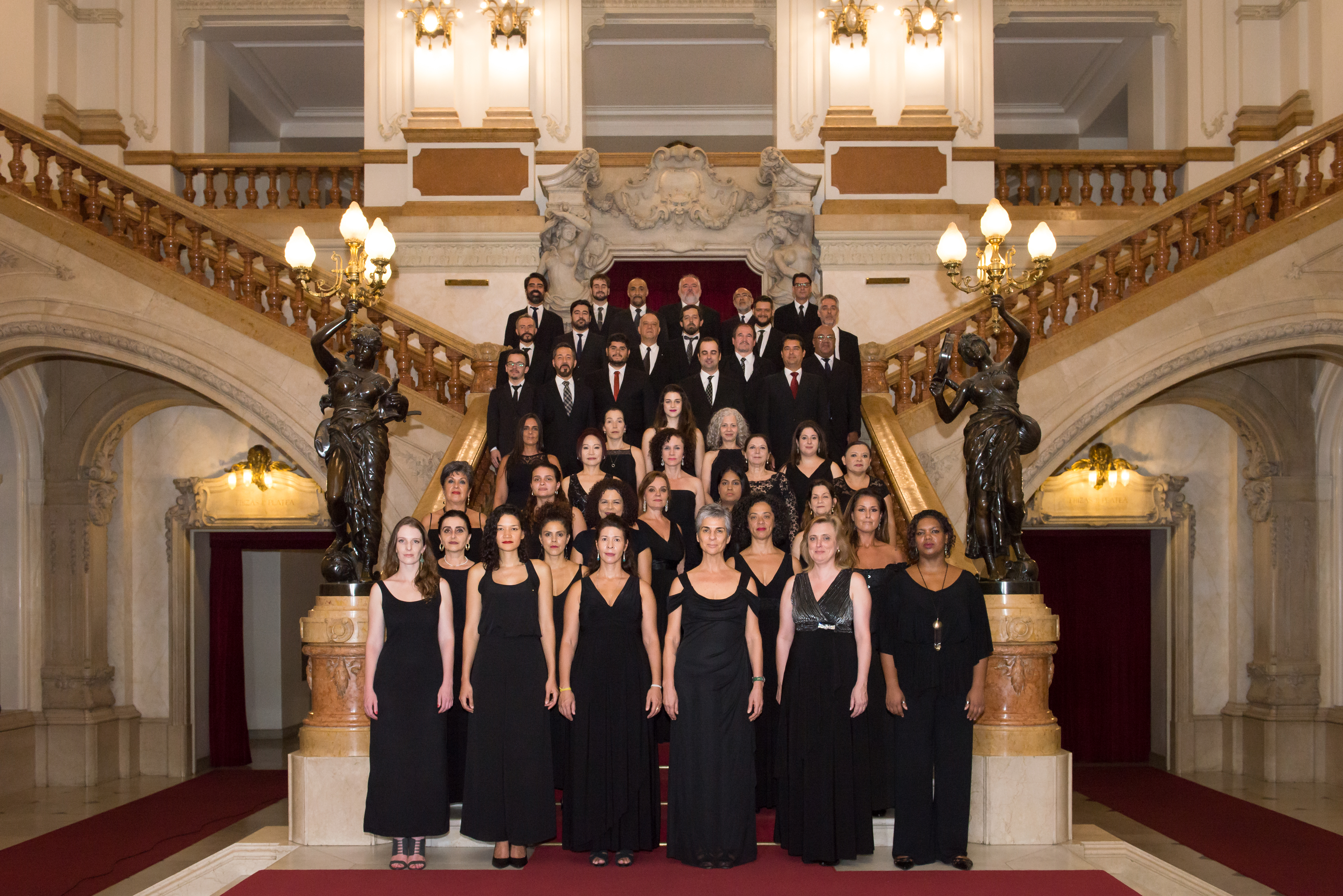Cantores do Coral Paulistano vestem preto e estão posicionados na estacaria interna do Theatro Municipal