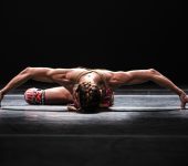 Bailarino com o corpo e o rosto próximos ao chão