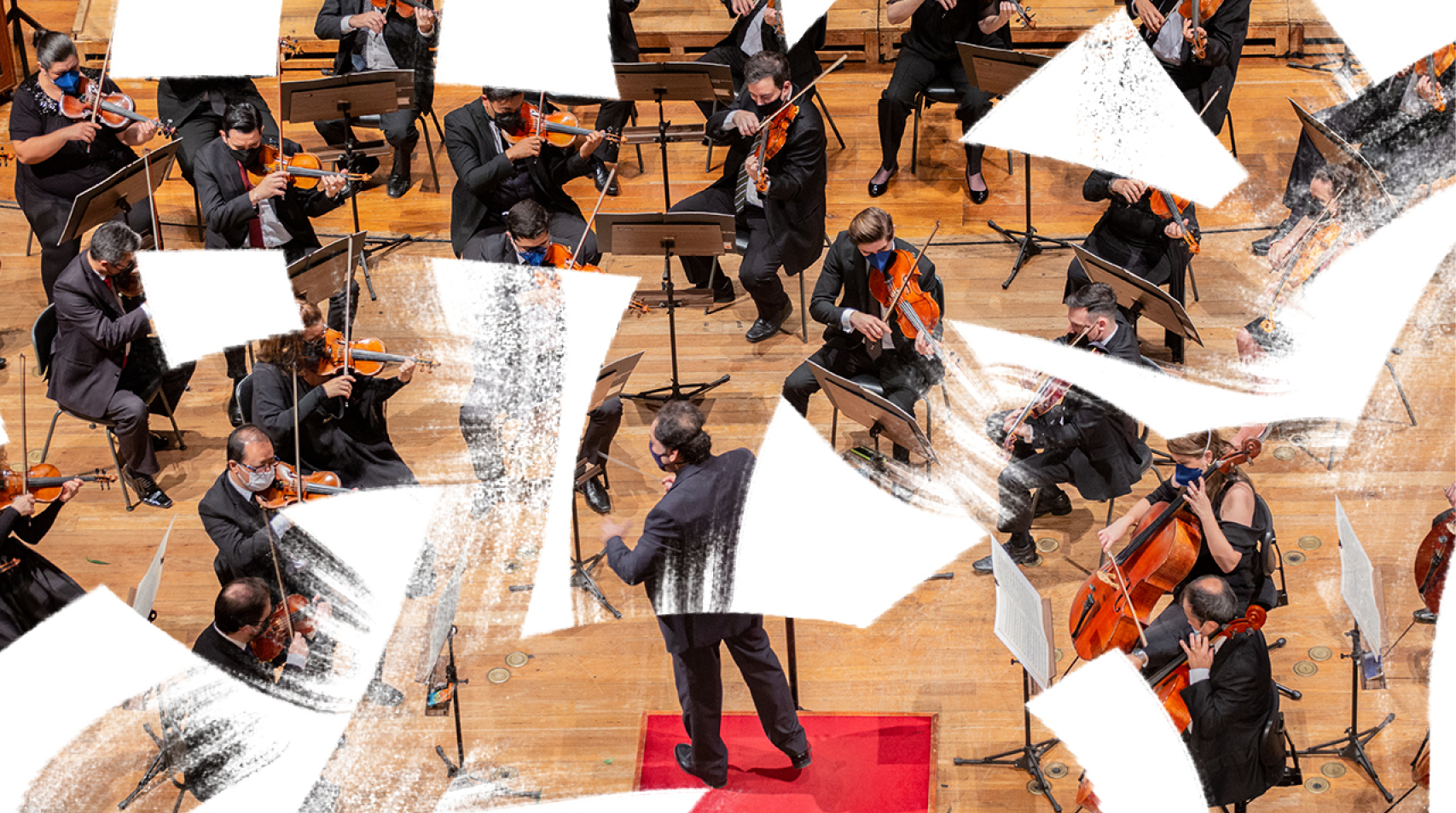 Foto de regente ao centro enquanto a orquestra toca