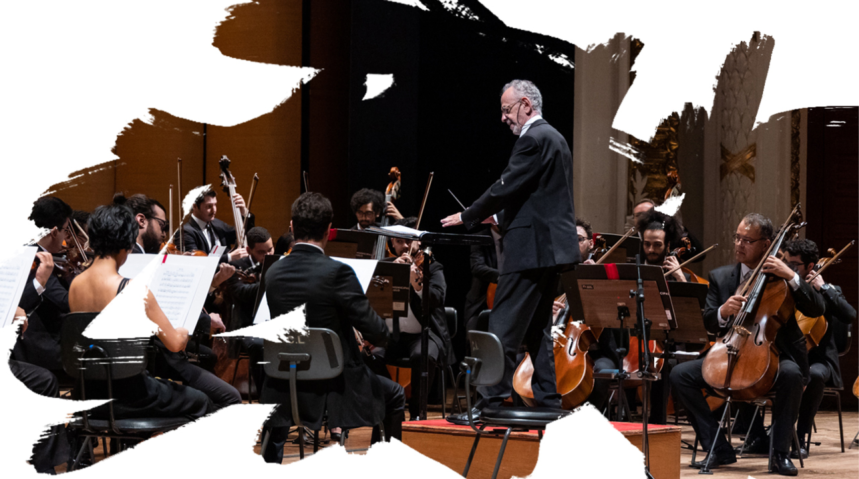 Foto do maestro regendo a orquestra durante um concerto