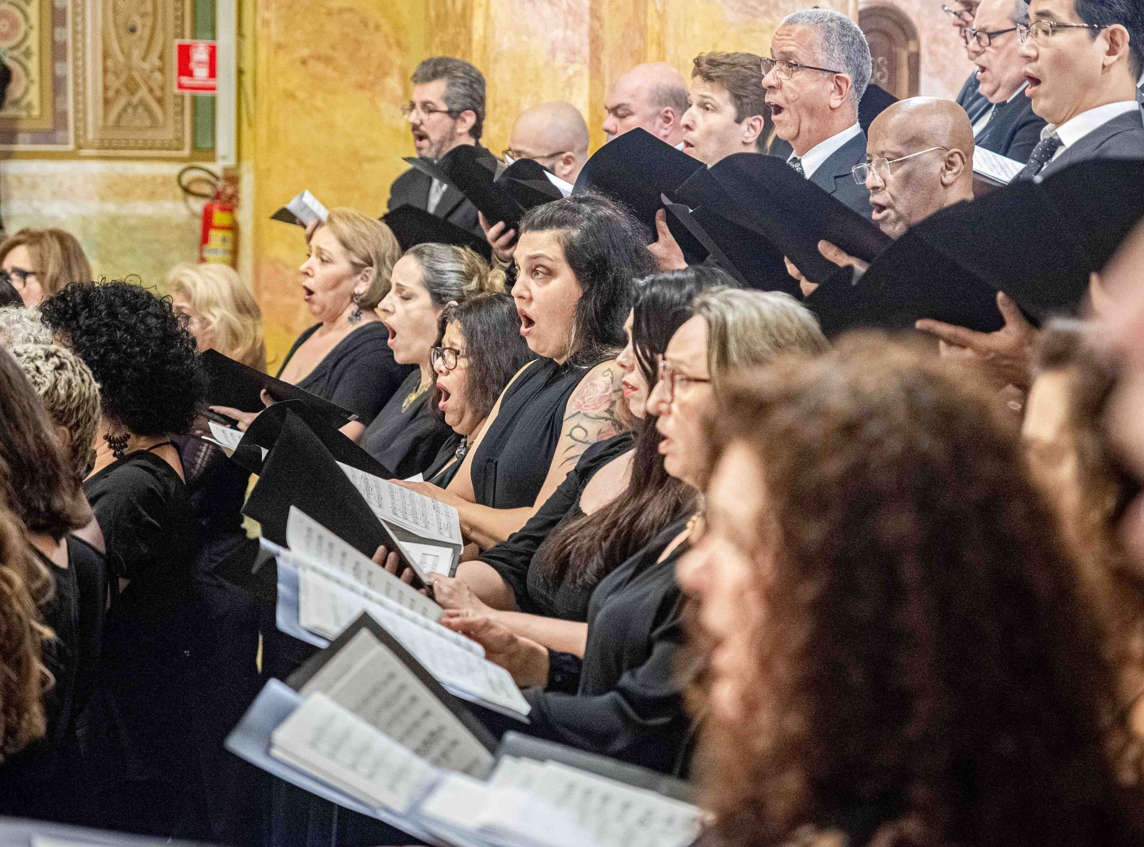 Foto de integrantes do Coro Lírico cantando durante uma apresentação