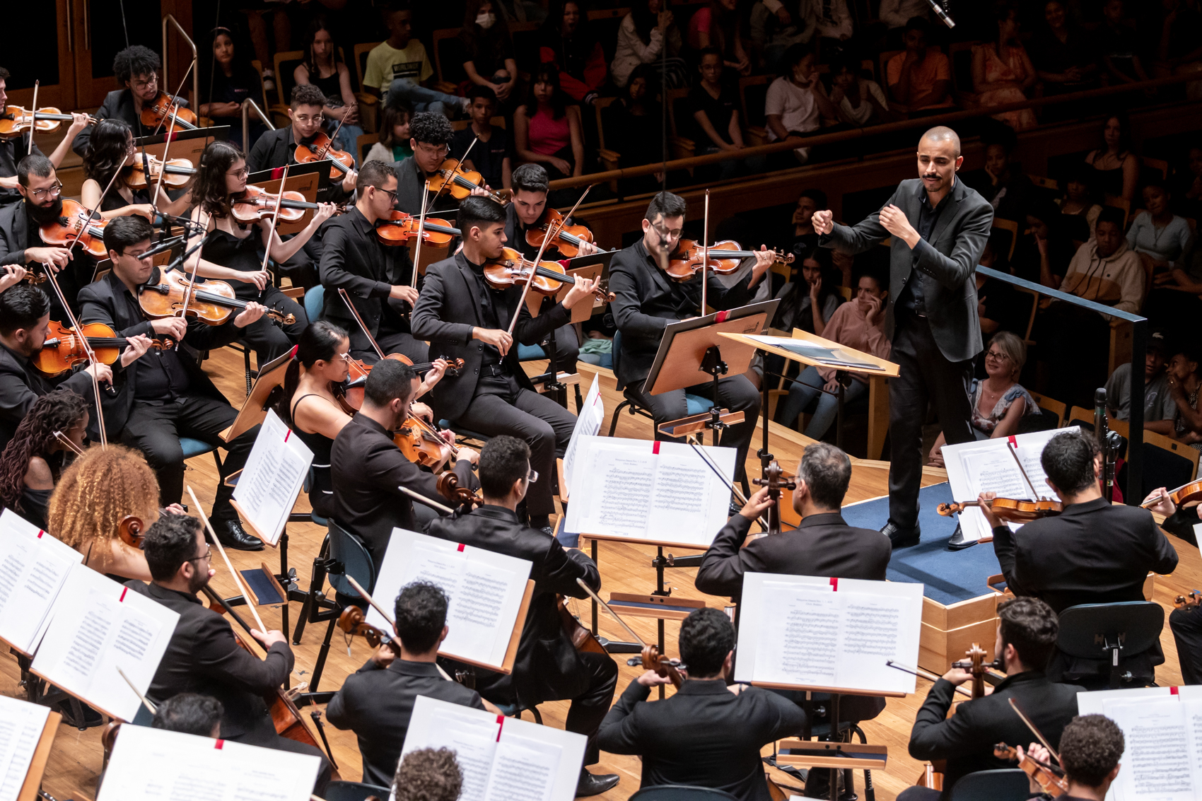 Foto de maestro regendo uma orquestra completa durante um concerto