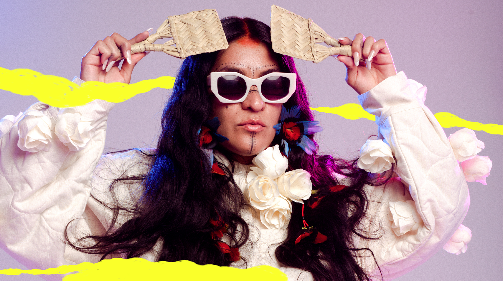 Foto da artista Brisa Flow, mulher com cabelos longos e olhos escuros com pinturas e acessórios indígenas