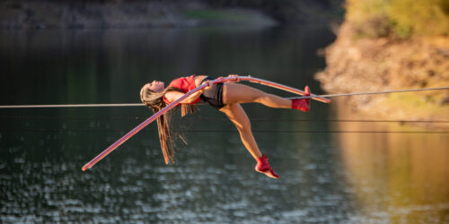Foto com artista circense atravessando numa corda sob um lago